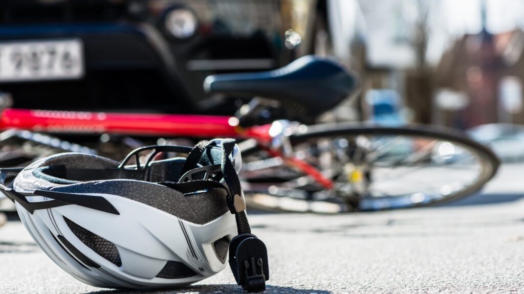 cyclist helmet with crashed bicycle in the background