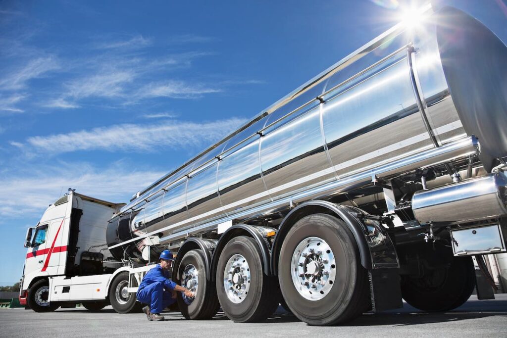 Worker performing a maintenance check on a tanker truck to avoid accident