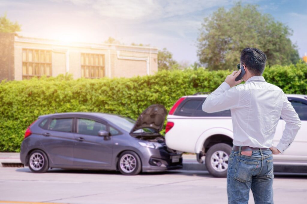 A man making a phone call after car crash accident on street