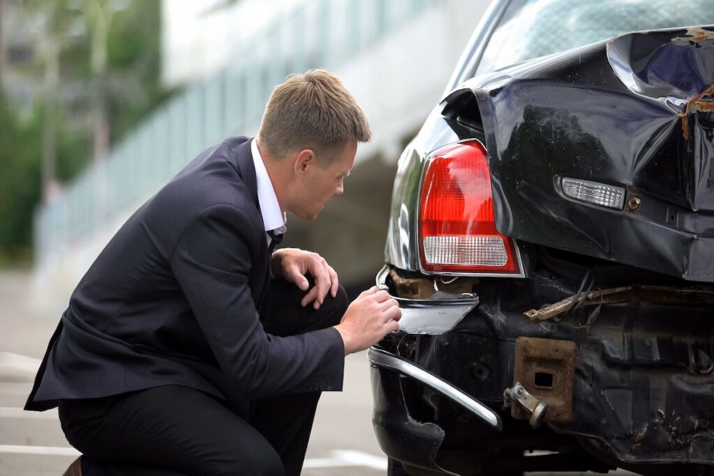 A man looking at the car damages after an accident