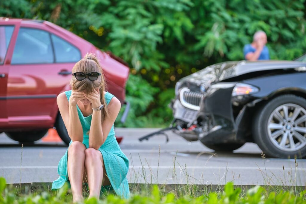 Sad female driver sitting on street side shocked after car accident