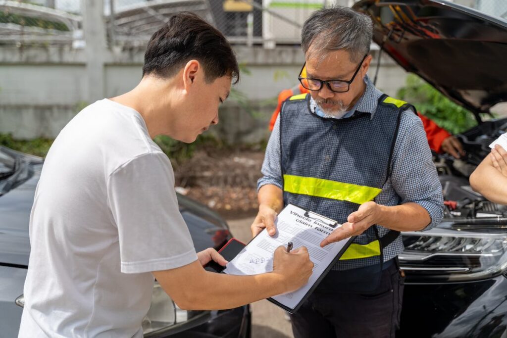 A Hartford car insurance agent showing the male customer where to sign the car insurance claim form