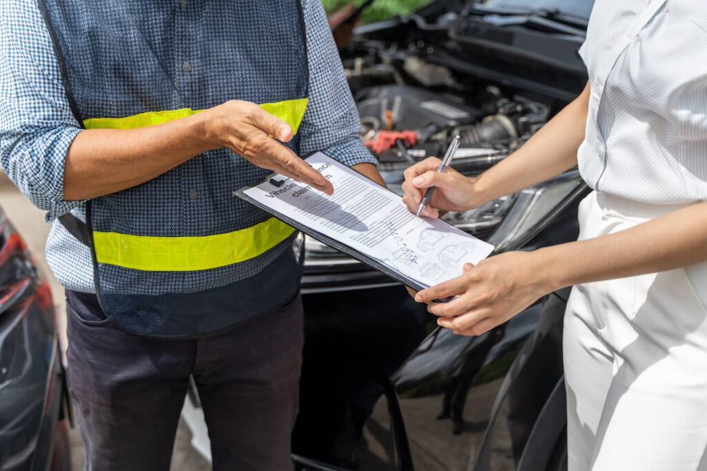 Close up of a Mercury auto insurance agent showing the woman customer where to sign the car insurance claim form