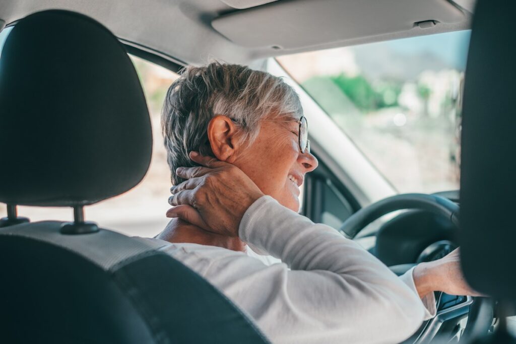 Rear view of an old woman having neck pain due to soft tissue injury after a car accident